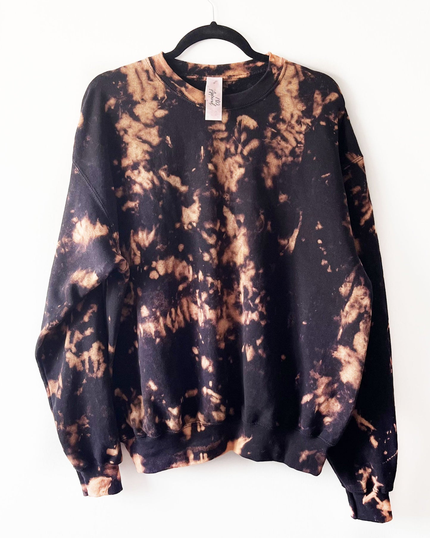 a black crewneck sweatshirt with orange bleach crumple pattern