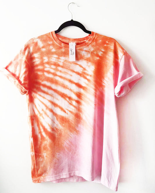 a crewneck t shirt with half and half diagonal design in orange and baby pink